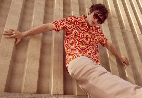 Trendy men's fashion collection featuring a bold patterned shirt and stylish sunglasses against a modern backdrop