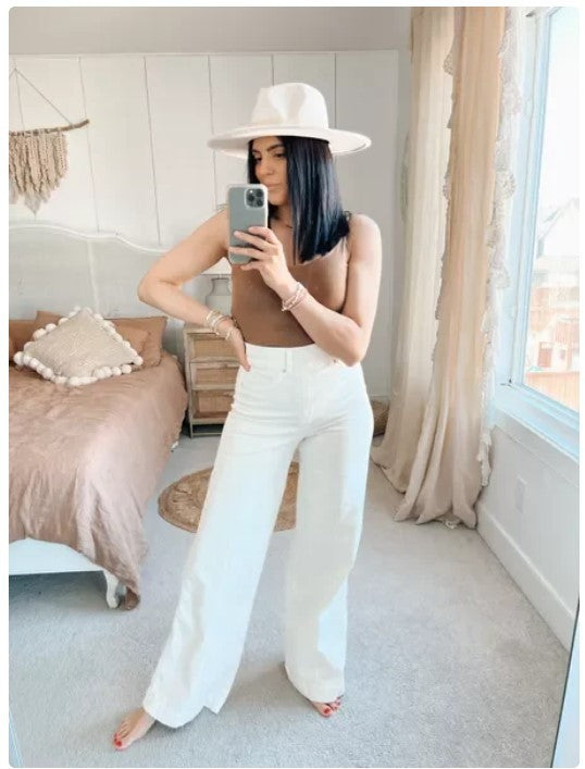 Chic model wearing MONO//FIT high waist wide leg jeans styled with a brown top and white hat