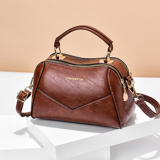 Stylish crossbody handbag in brown with gold accents and dual handles for versatile use