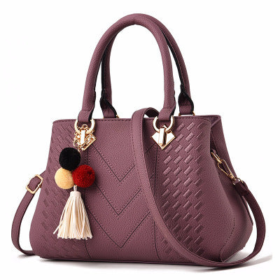 MONO//FIT Luxury ladies handbags in purple featuring a stylish tassel and decorative pom-poms