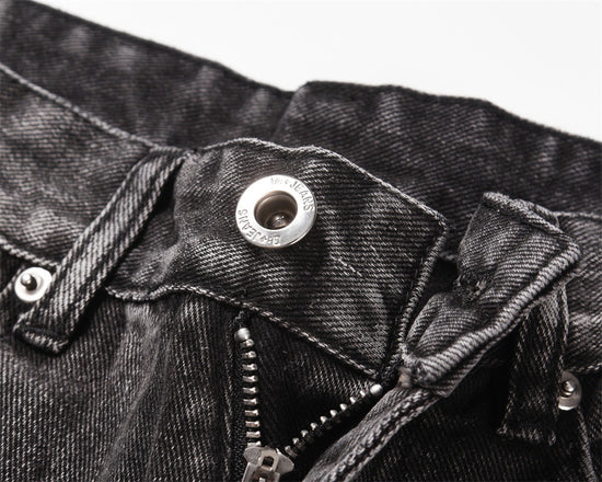 Close-up of MONO//FIT men's distressed wide-leg jeans with button and zipper detailing